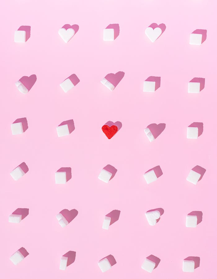 Unique arrangement of sugar cubes with a red heart on a soft pink background. Perfect for Valentine's or uniqueness concept imagery.
